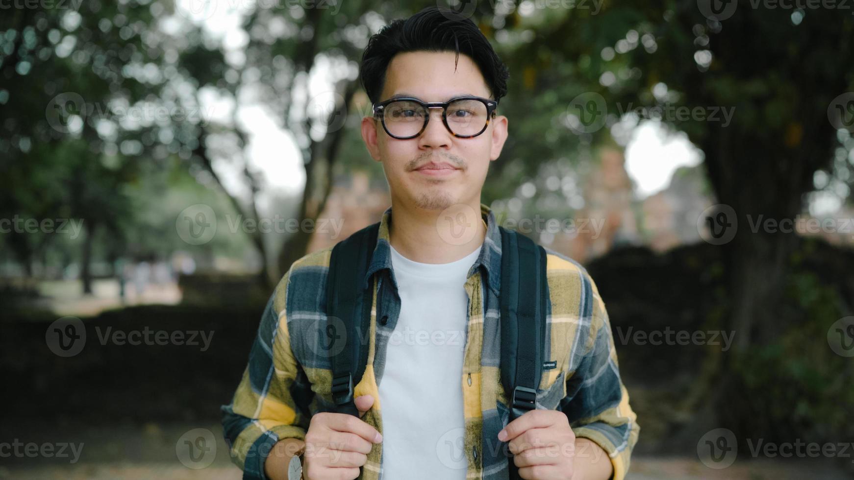 uomo asiatico viaggiatore che si sente felice sorridendo al viaggio di vacanza della fotocamera ad ayutthaya, thailandia, maschio zaino in spalla godersi il suo viaggio in un punto di riferimento incredibile nella città tradizionale. gli uomini di stile di vita viaggiano il concetto di vacanze foto