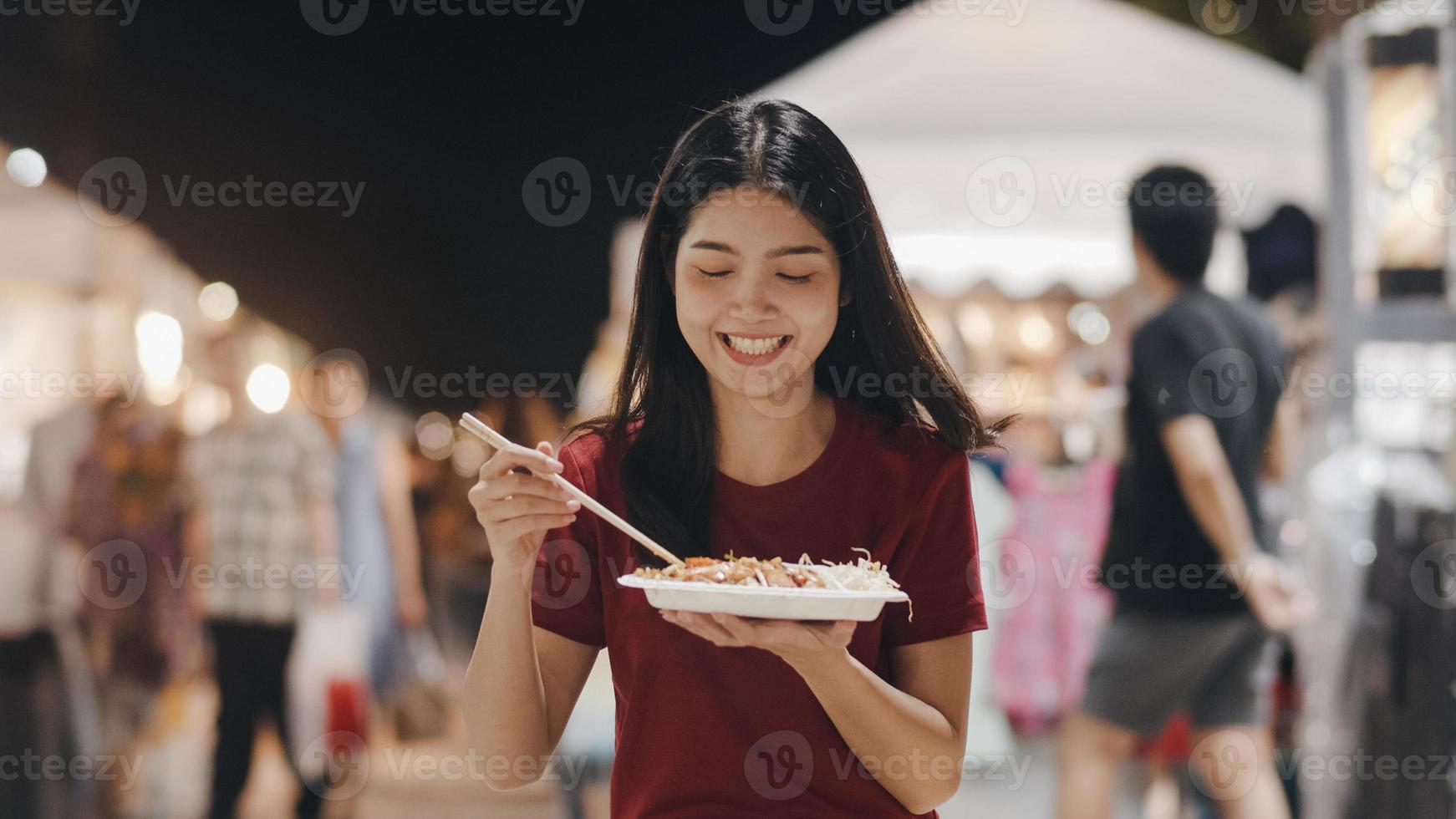 viaggio asiatico della giovane donna a bangkok, tailandia, bella femmina che si sente felice camminando e mangiando il pad thai alla strada di khao san. le donne viaggiano mangiano cibo di strada nel concetto di thailandia. foto