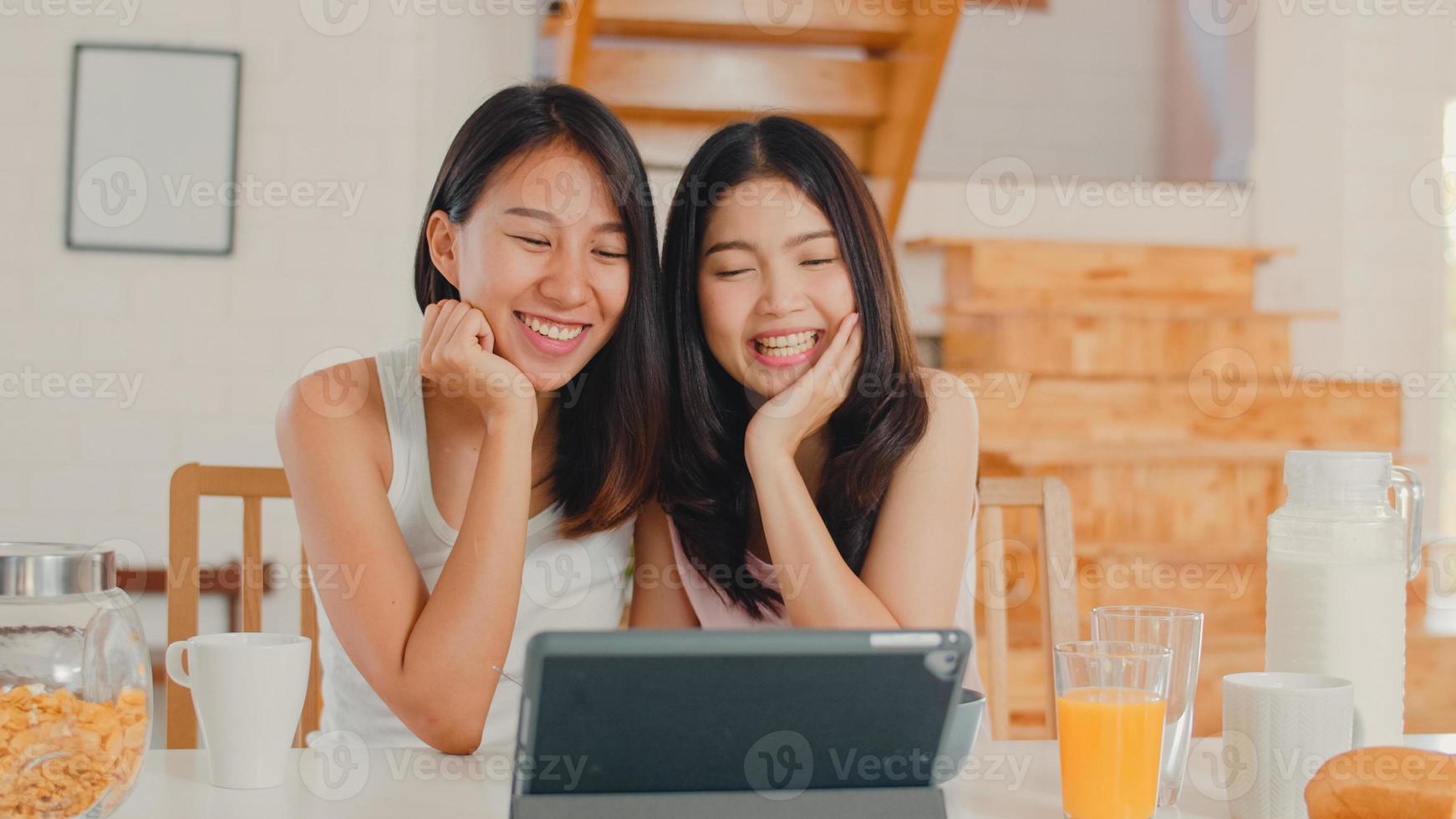 Lesbiche asiatiche influencer lgbtq donne coppia vlog a casa, giovani ragazze amante asiatiche felici usando tablet registrare video vlog nei social media mentre fanno colazione in cucina a casa al mattino concetto. foto