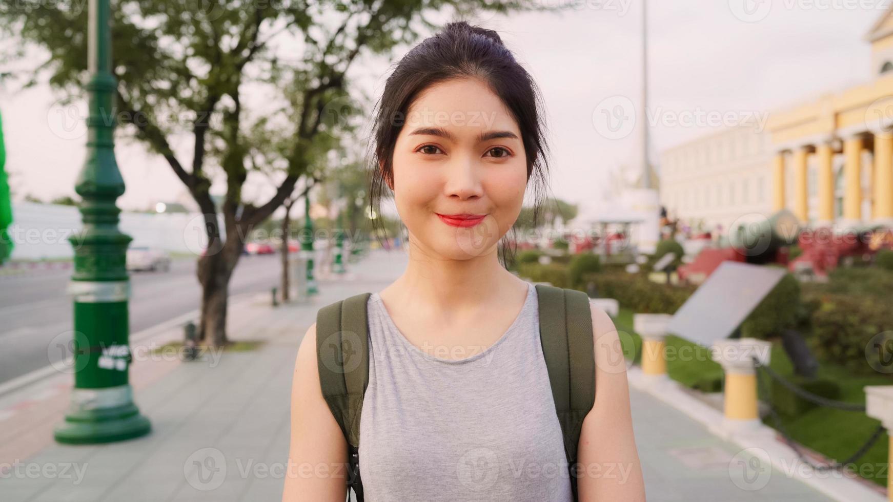 donna asiatica del viaggiatore che si sente felice sorridente alla macchina fotografica viaggio di vacanza a bangkok, tailandia, donna asiatica con zaino e sacco a pelo godersi il loro viaggio in un punto di riferimento straordinario nella città tradizionale. ritratto guardando la fotocamera. foto