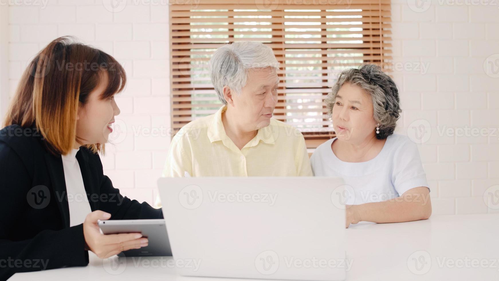 l'agente femminile intelligente dell'asia offre l'assicurazione sanitaria per le coppie anziane tramite documento, tablet e laptop. coppia asiatica invecchiata che si consulta con l'agente assicurativo mentre si siede insieme a casa. foto