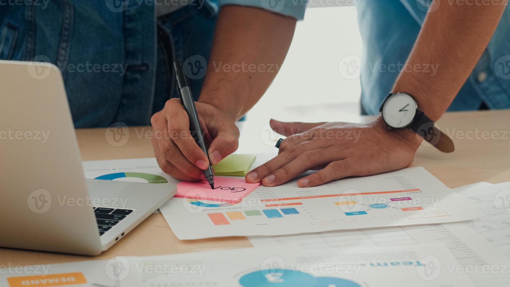 giovane riunione del team creativo asiatico che lavora al computer portatile. gruppo di uomini e donne d'affari che cercano carta per documenti, discutono e pensano a una nuova idea, situazione aziendale, lavoro di squadra nel concetto di ufficio moderno. foto