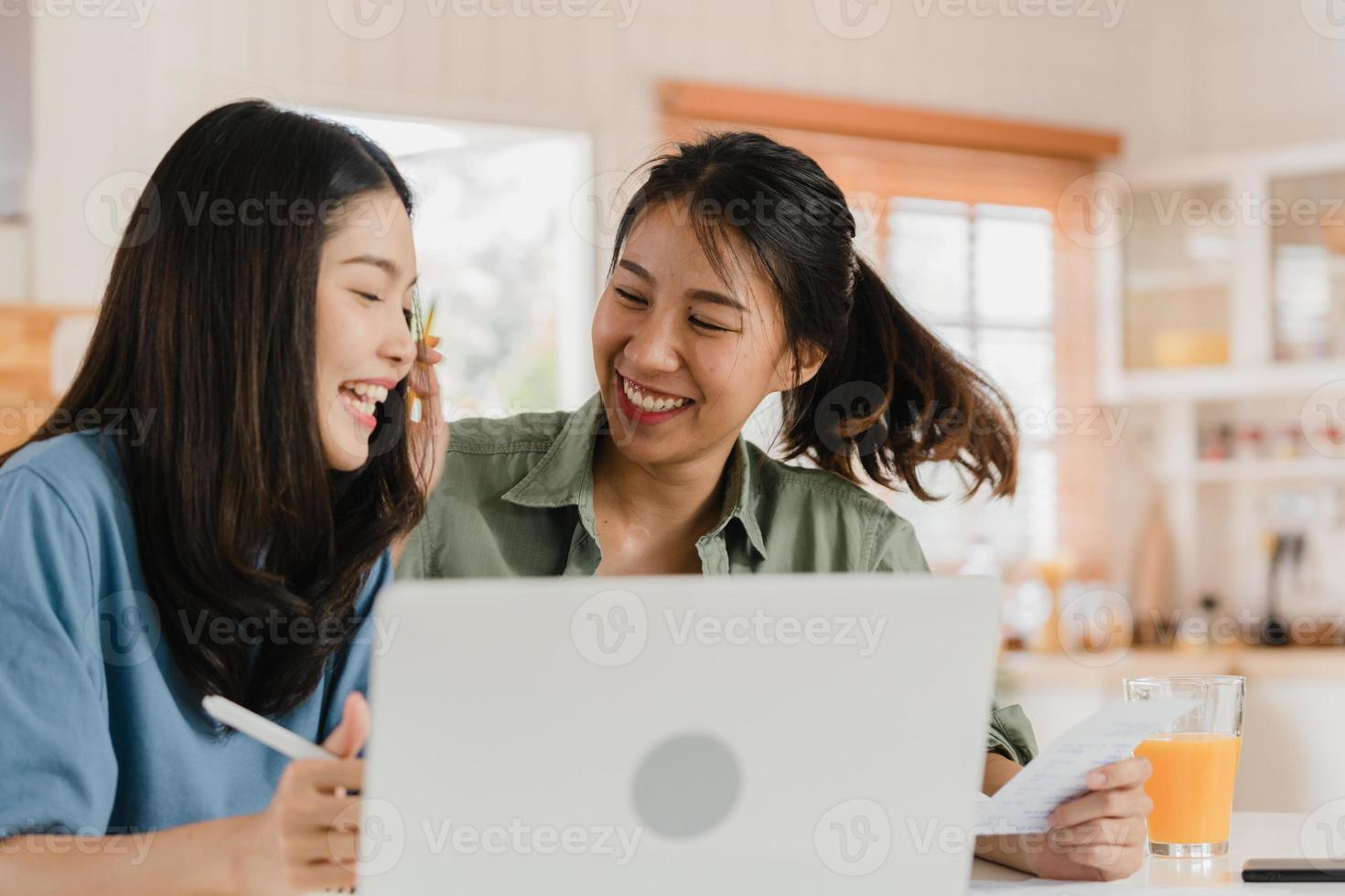 le coppie di donne lgbtq asiatiche d'affari fanno un account a casa, giovane ragazza asiatica che utilizza la calcolatrice registra il budget, le tasse, il documento finanziario sul computer portatile che lavora nel concetto di cucina. foto