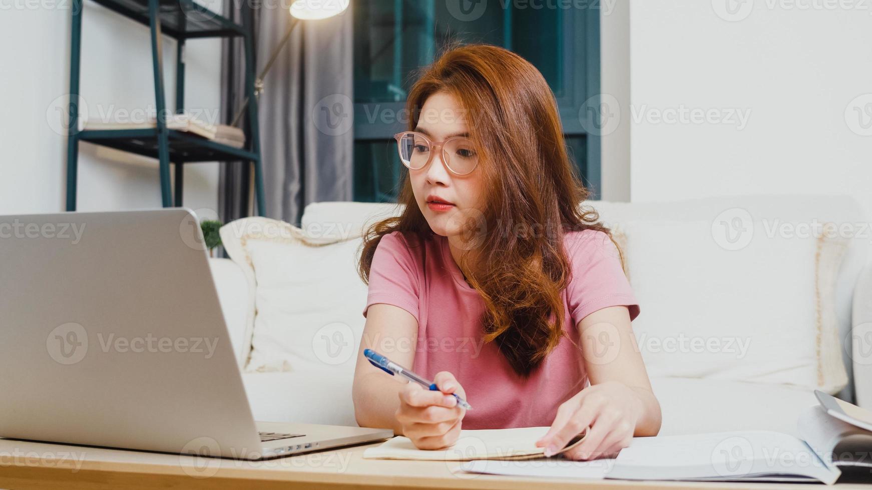 lezione di apprendimento a distanza per giovani studentesse asiatiche con insegnante online e studio su computer portatile in soggiorno da casa di notte. distanziamento sociale, quarantena per la prevenzione del virus corona. foto