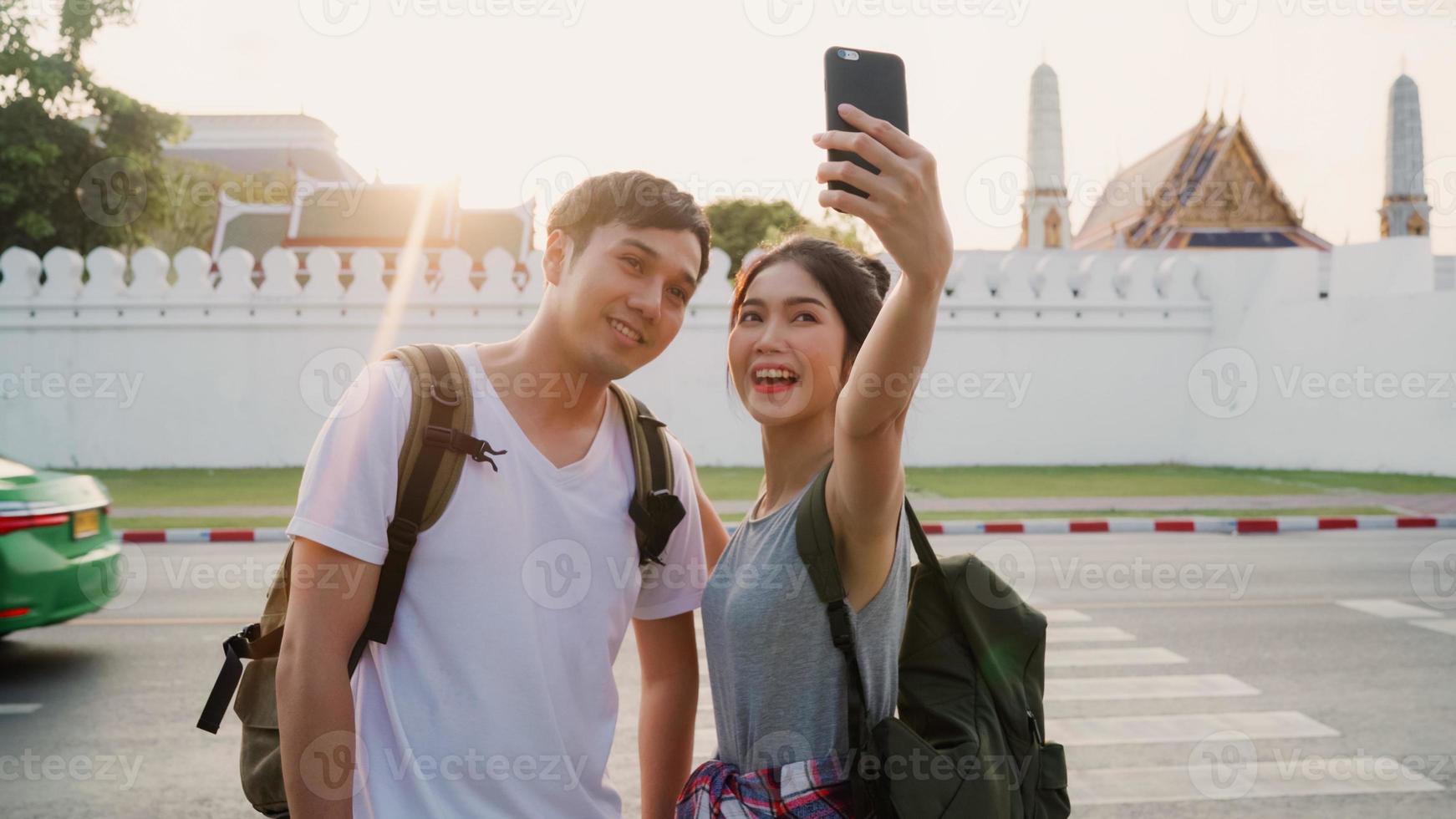 coppia di blogger asiatici viaggiano a bangkok, in tailandia, dolce coppia utilizzando il selfie del telefono cellulare e la visualizzazione di foto mentre trascorrono del tempo dolce in un viaggio di vacanza al tramonto. le coppie viaggiano nel concetto di città.