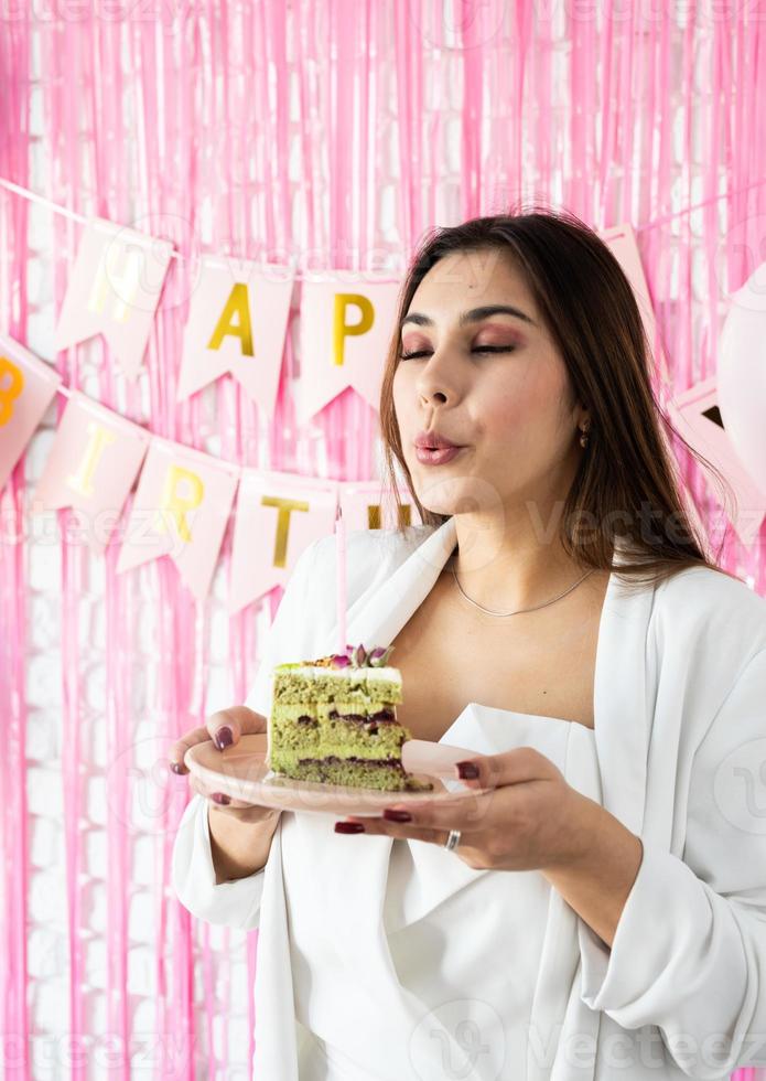 bella donna che celebra la festa di compleanno che tiene un pezzo di torta che fa il desiderio foto