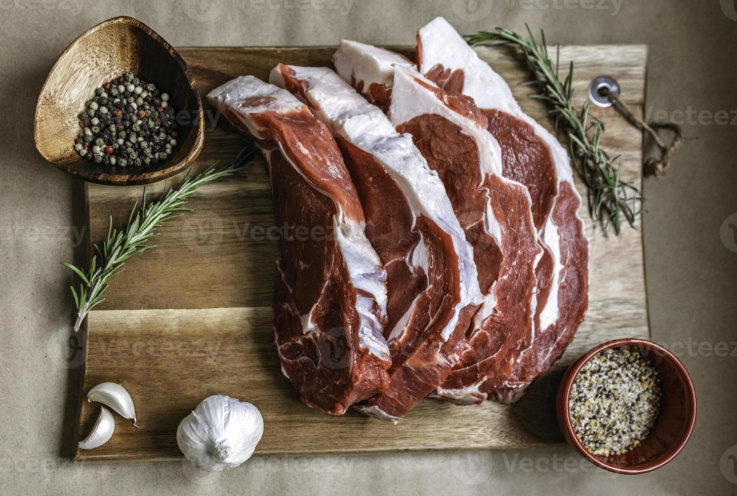 bistecca di costata biologica nutrita con erba su tavola di legno, specie di sfondo di carta. carne di manzo, carne cruda. costata di manzo biologica canadese dal gusto incredibile. ribeye è privo di OGM, steroidi, ormoni e antibiotici foto