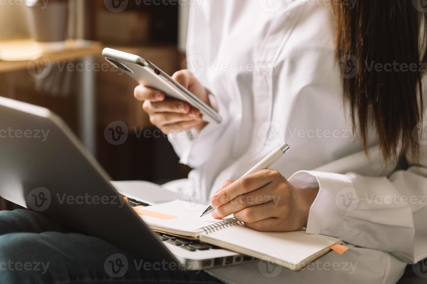 giovane impresa motivata che pianifica la sua strategia mentre digita su laptop, tablet e scrive su notebook foto