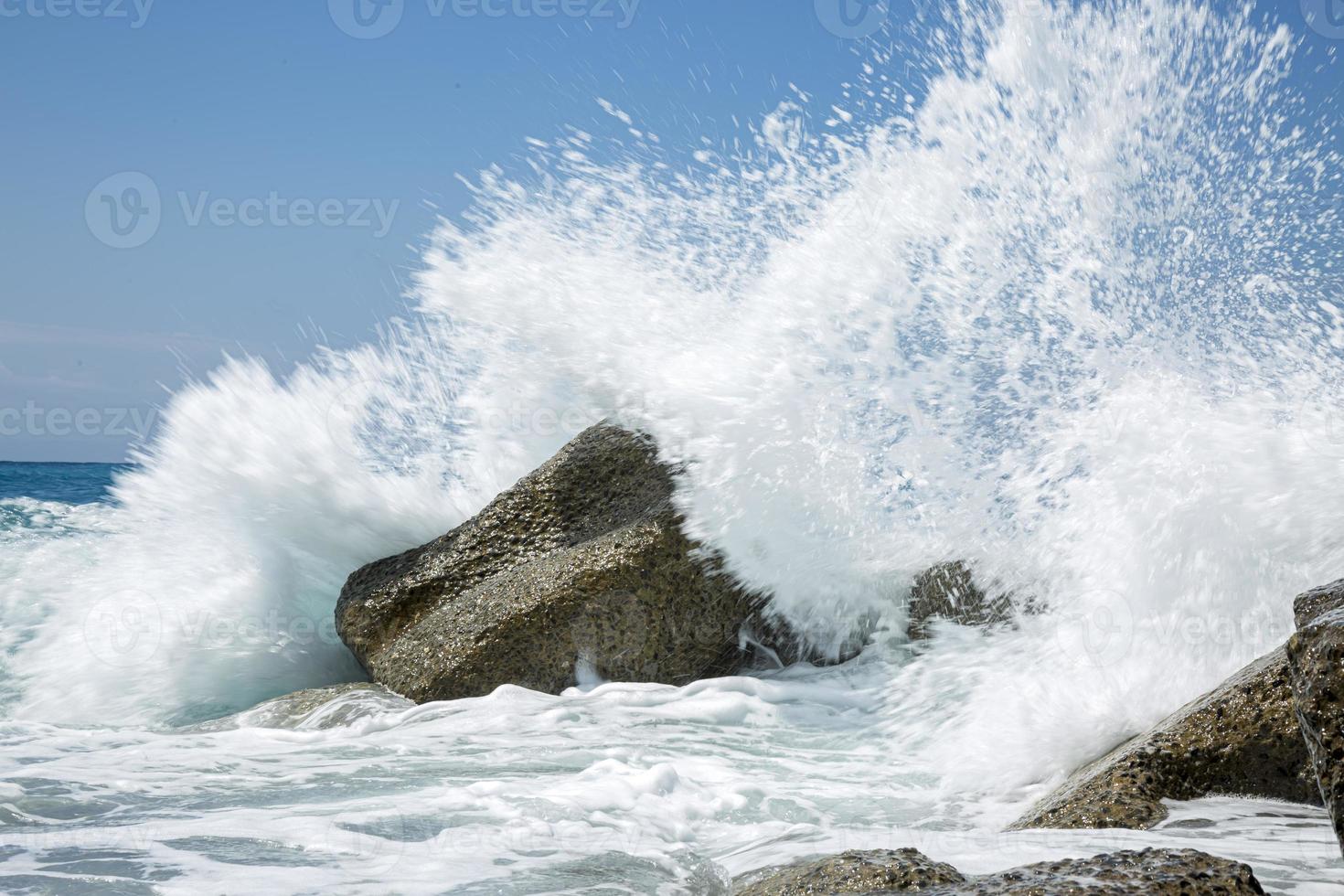 onda alta che si infrange sugli scogli della costa. foto