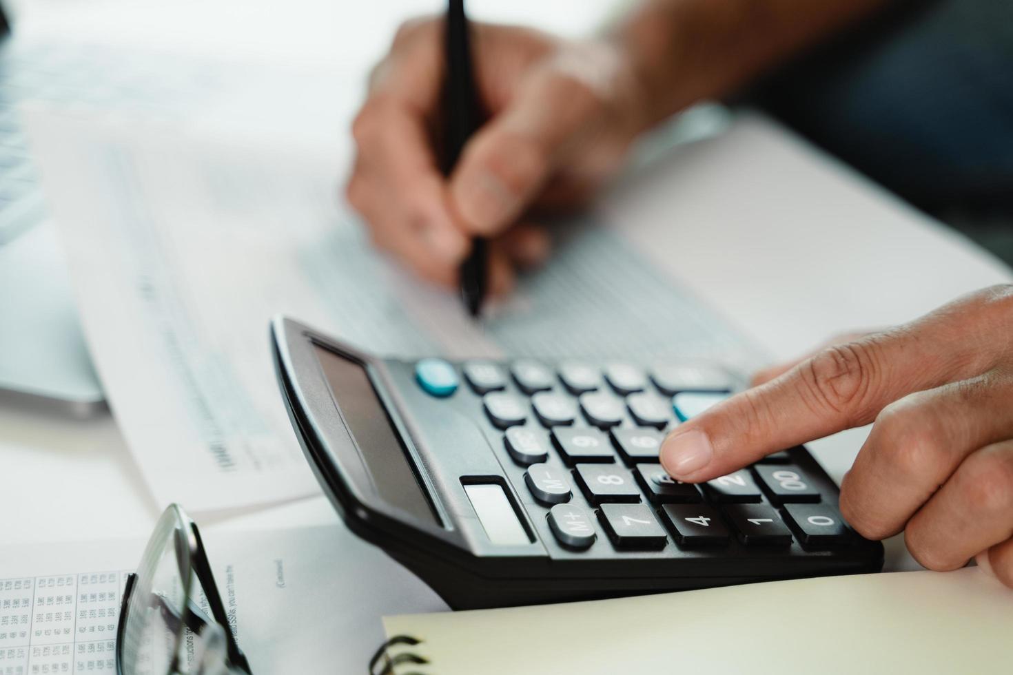 l'uomo sta calcolando l'imposta annuale con il calcolatore e il modulo di compilazione della dichiarazione dei redditi individuale. stagione per pagare le tasse e il concetto di pianificazione del budget. foto