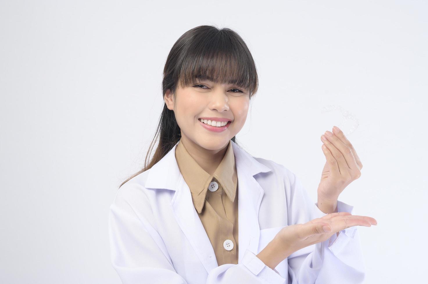 giovane dentista femminile che tiene parentesi graffe invisalign su sfondo bianco studio, assistenza sanitaria dentale e concetto ortodontico. foto