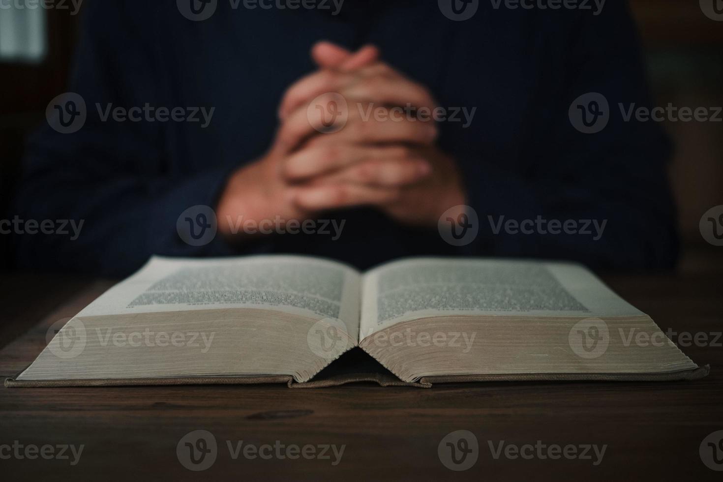 l'uomo sta leggendo e pregando la Scrittura o la Sacra Bibbia su un tavolo di legno con spazio per la copia. religione, credo concetto. foto