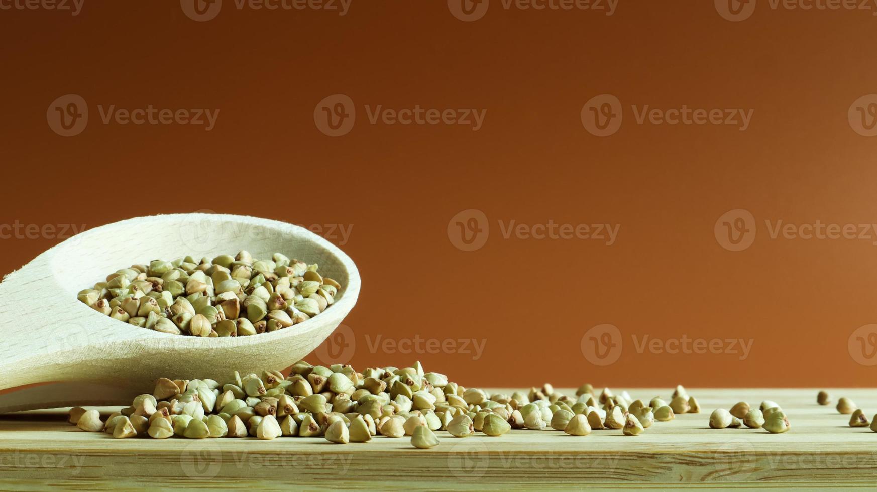 grano saraceno verde in un cucchiaio di legno su sfondo marrone. ottimo cibo. semole sane. cibo vegetariano crudo biologico non fritto. il concetto di una dieta sana ed equilibrata. cibi dietetici. copia spazio foto