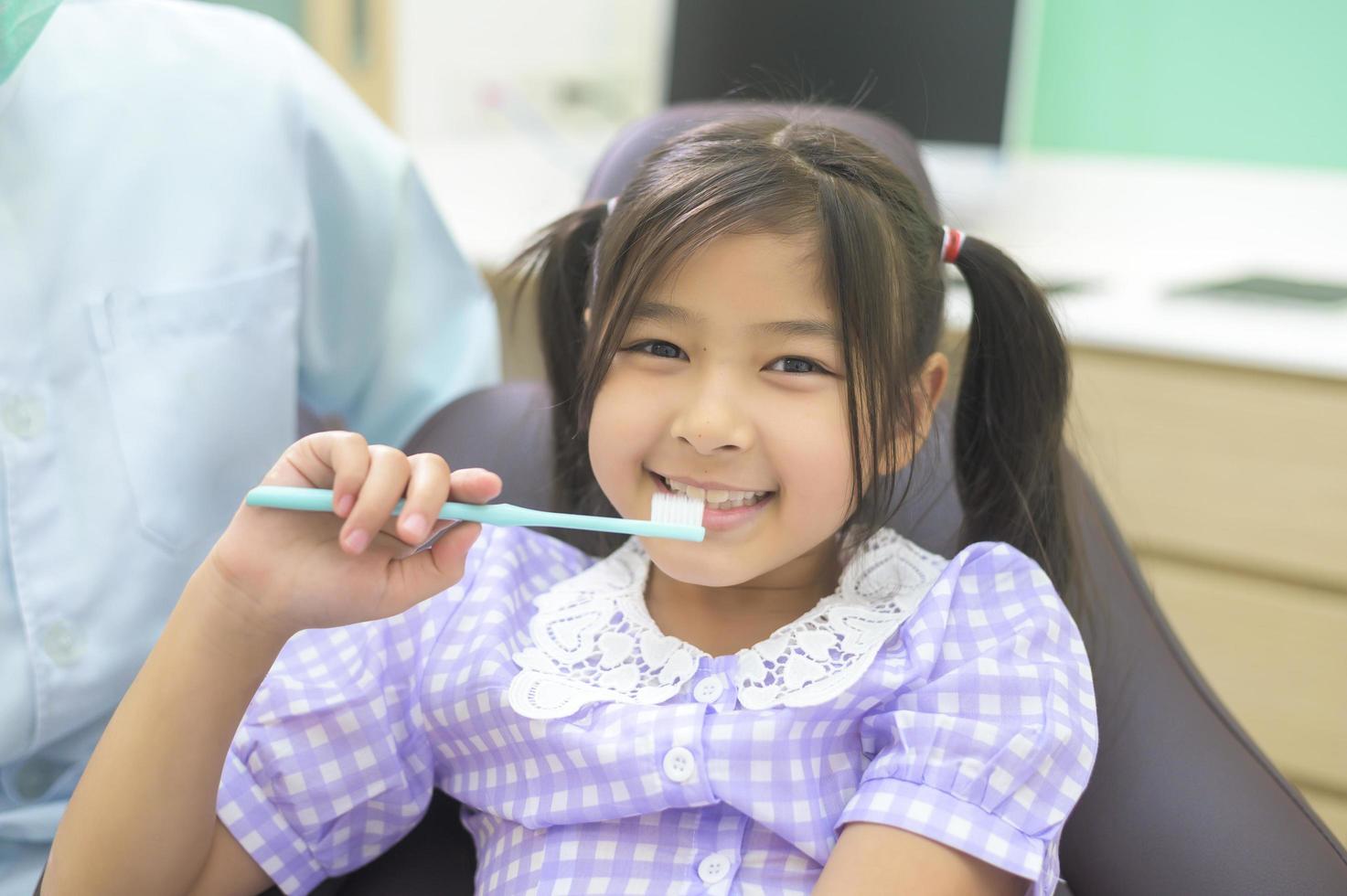 dentista femminile che dimostra come lavare i denti a una bambina in clinica dentale, controllo dei denti e concetto di denti sani foto