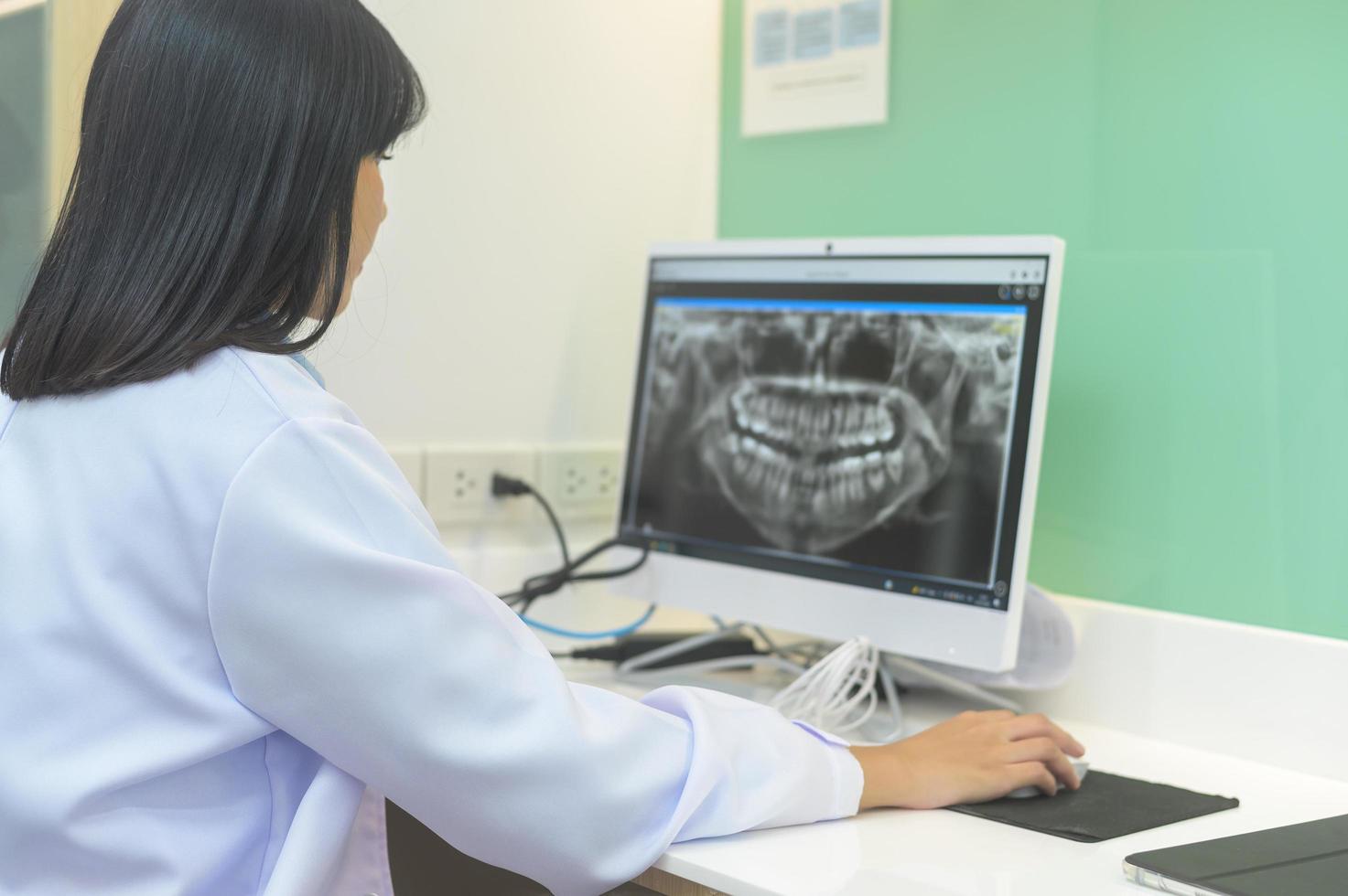 dentista femminile che lavora con i raggi x dei denti sul computer portatile in clinica odontoiatrica, controllo dei denti e concetto di denti sani foto