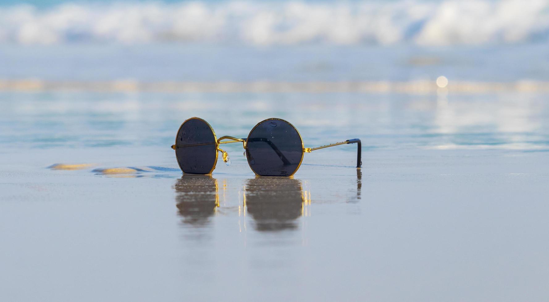 occhiali da sole sulla sabbia bellissima spiaggia estiva foto