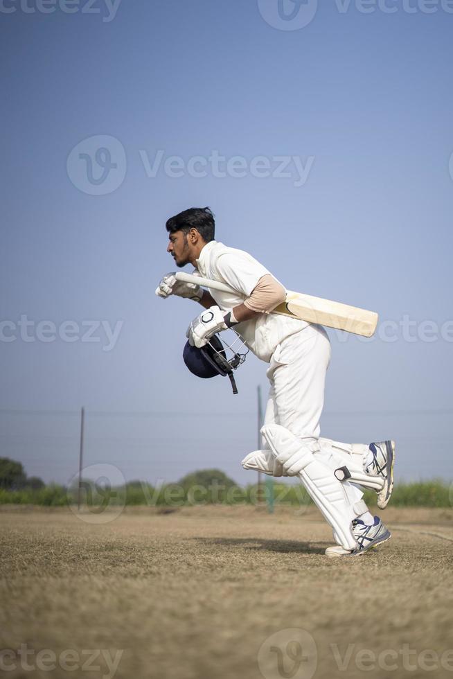 giovane giocatore di cricket indiano che entra nel campo di cricket. concetto di cricket e sport indiano. foto