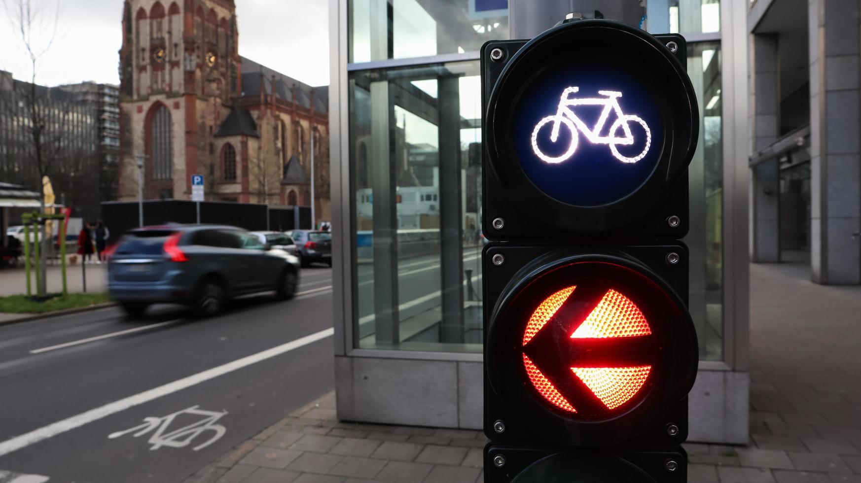 dusseldorf, germania - 28 febbraio 2020. primo piano semaforo per biciclette con una città trafficata sullo sfondo a un bivio in germania. i ciclisti aspettano che un semaforo attraversi la strada. foto