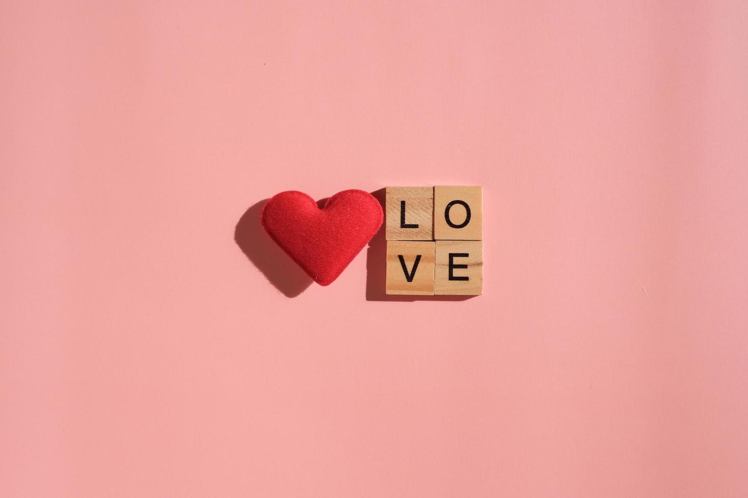 cuore rosso isolato su sfondo rosa con lettere amore. san valentino, regalo, messaggio dell'amante, biglietto di auguri. concetto di amore. foto