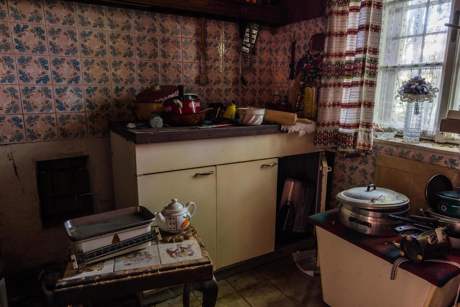 cucina in una casa abbandonata con una bilancia e vecchie pentole foto