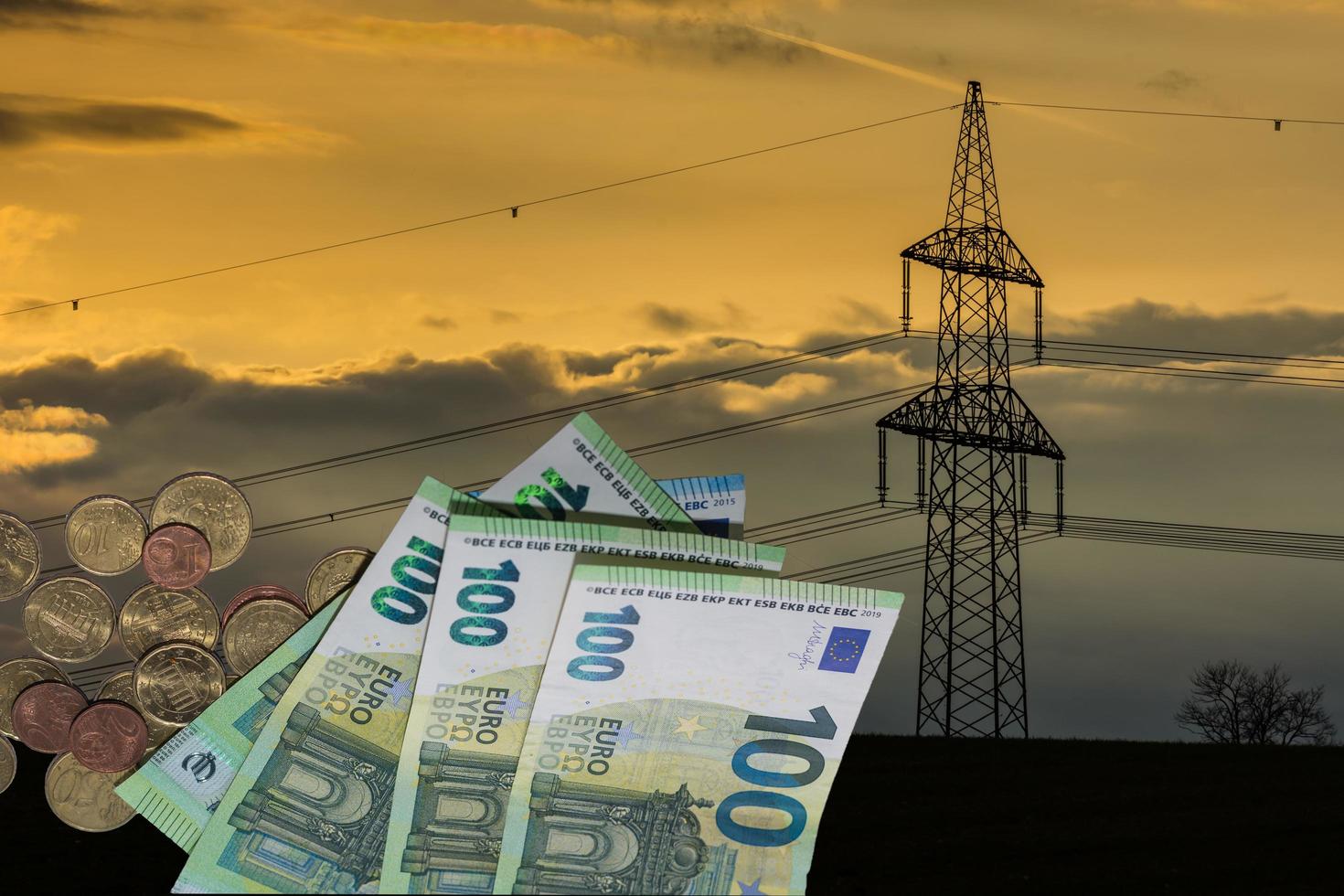 traliccio dell'elettricità al tramonto con banconote e monete da 100 euro relative all'aumento del prezzo dell'energia elettrica foto