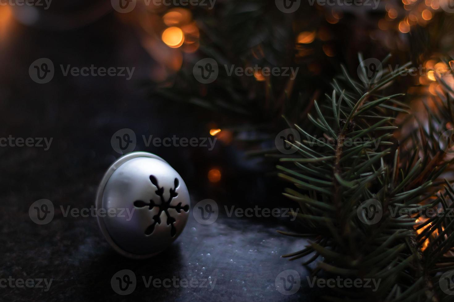 campana di natale d'argento su uno sfondo sfocato di un albero di natale e ghirlande. copia spazio foto