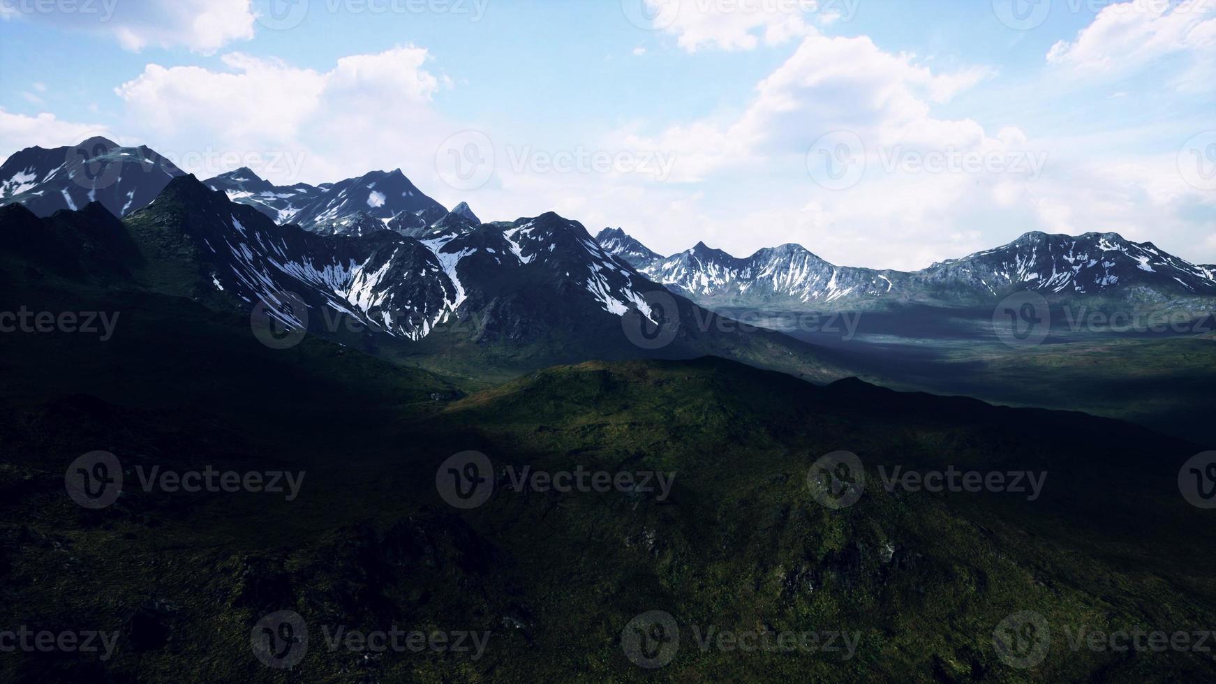 paesaggio soleggiato con vista sulle montagne innevate e sui prati foto