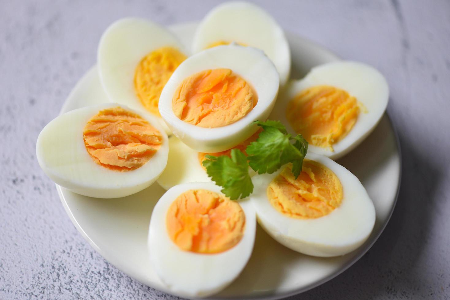 menu uova cibo uova sode in un piatto bianco decorato con foglie di coriandolo verde, tagliato a metà tuorli d'uovo per cucinare mangiare sano uova colazione foto