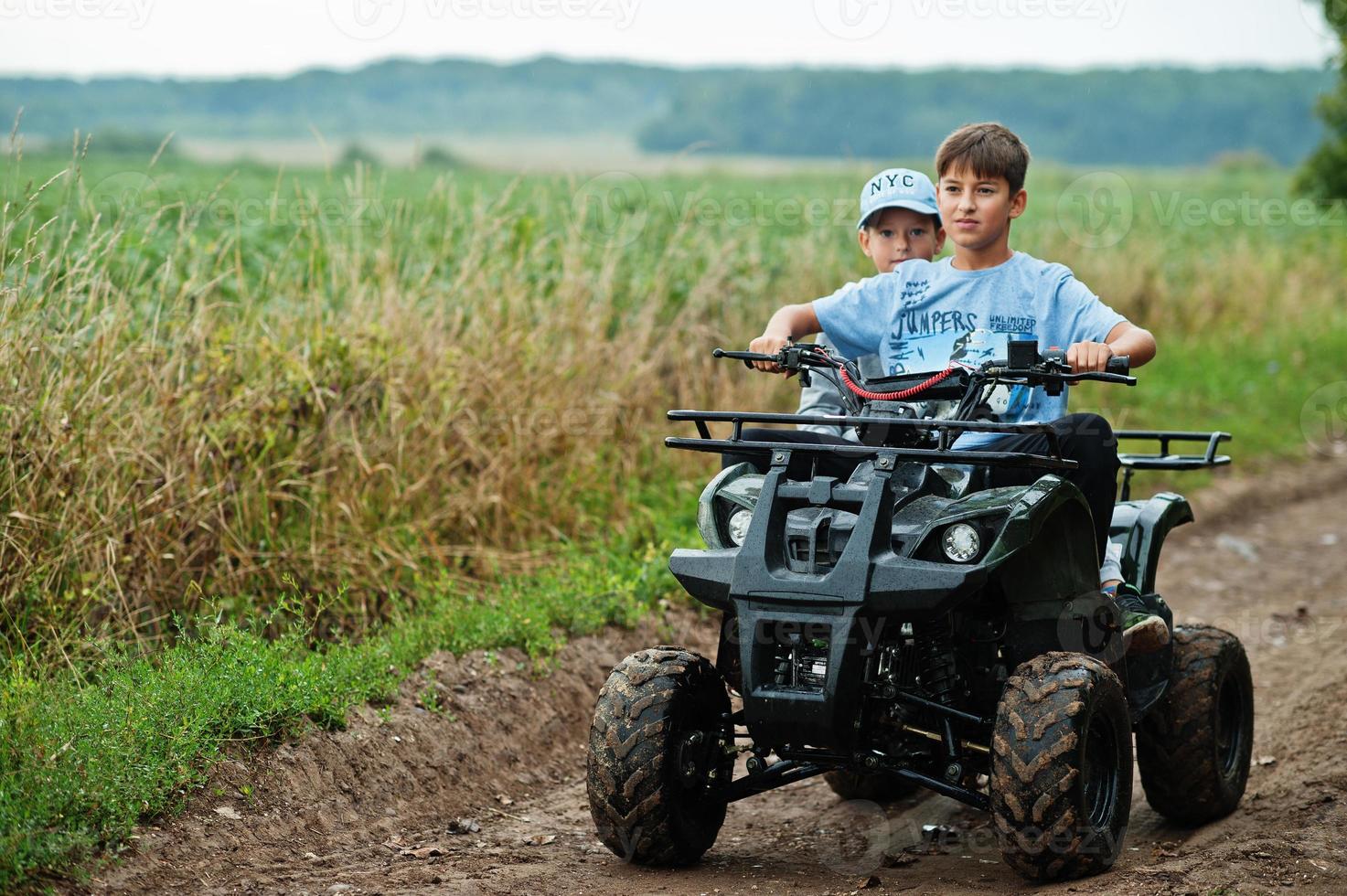 due fratelli che guidano un quad quad a quattro ruote. momenti felici dei bambini. foto