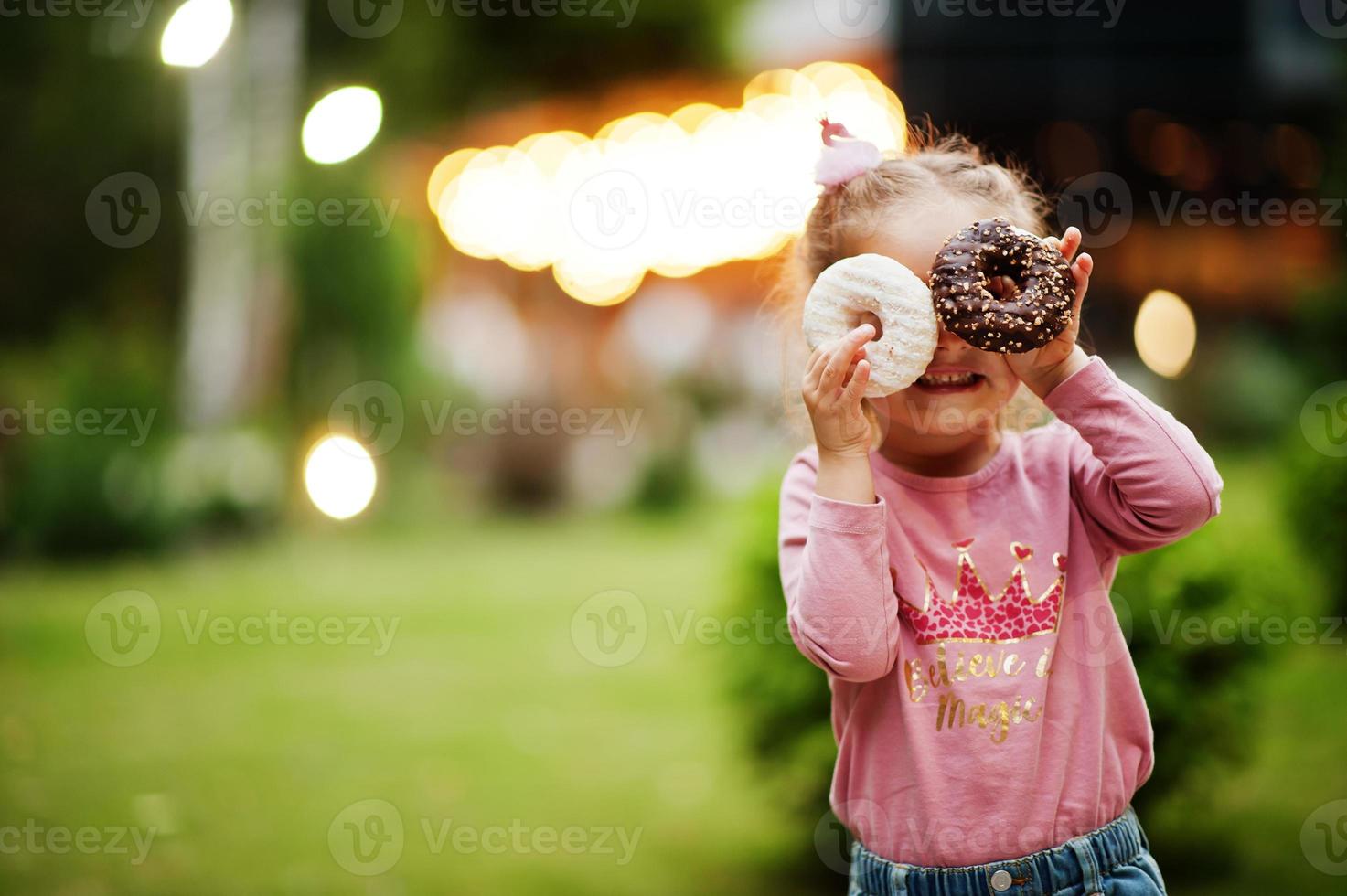bambina con ciambelle al cortile serale. gustoso cibo per ciambelle. foto