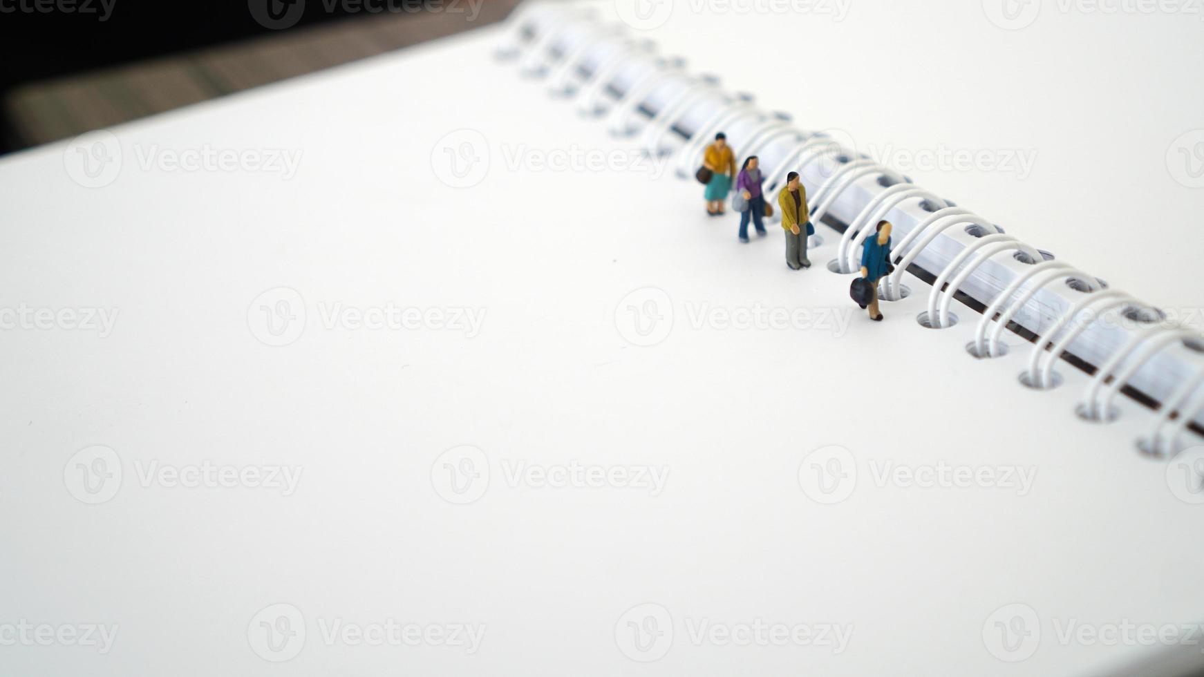 persone in miniatura in gruppo che camminano sul libro bianco bianco. concetto di business con copia spazio e spazio bianco per il testo o il design foto