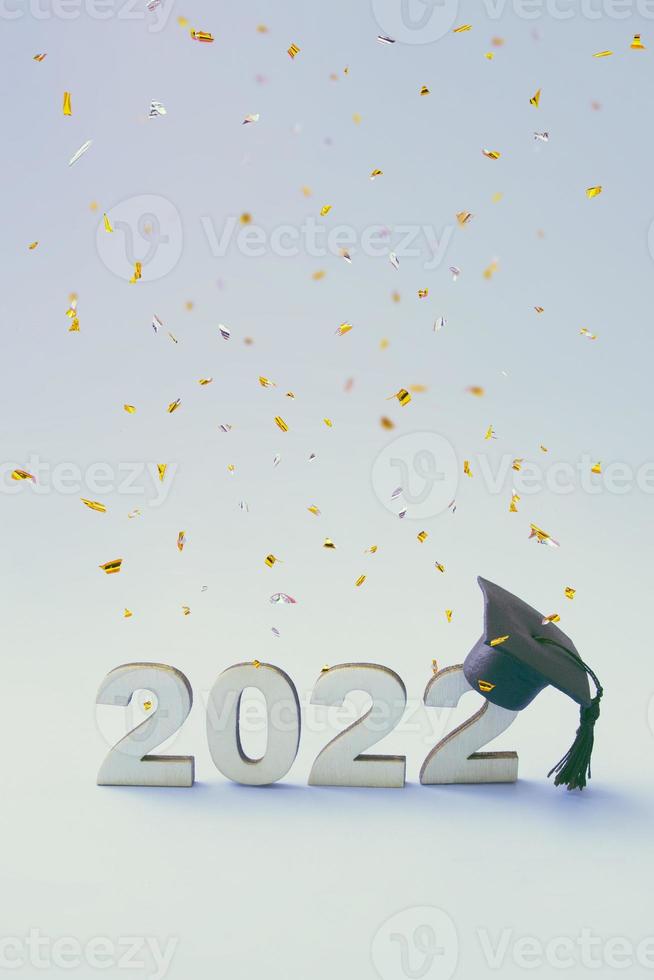 laurea 2022 con cappello da laureato su un numero 2022 in legno con coriandoli volanti foto