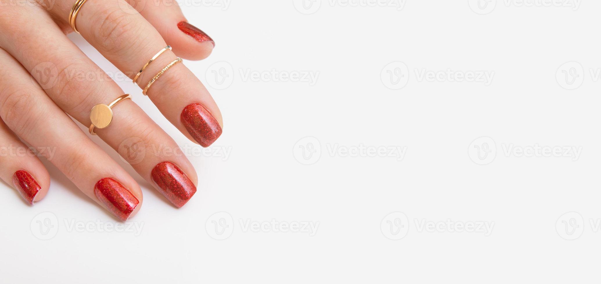 banner con smalto gel per manicure di colore rosso con scintillii sulle mani femminili con anelli. copia spazio foto