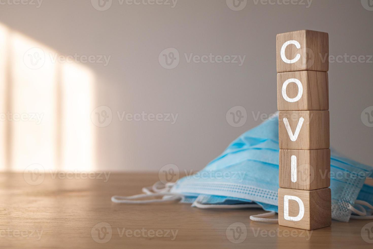 questo concetto mostra la campagna per indossare correttamente la maschera. blocchi di legno con testo, covid. maschera medica blu sul tavolo. protezione da malattie come influenza, influenza, covid, polvere, pm2.5. foto