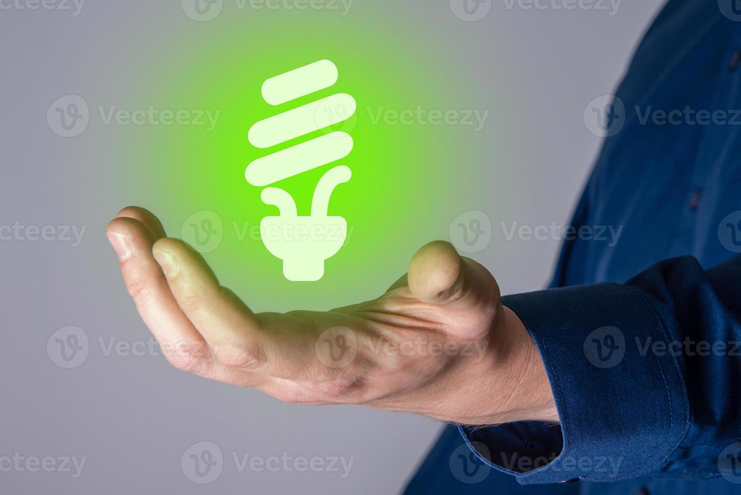 mani che tengono l'icona della lampadina a risparmio energetico. foto