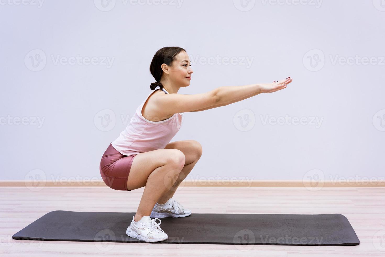 donna che fa fitness a casa sullo sfondo del muro foto