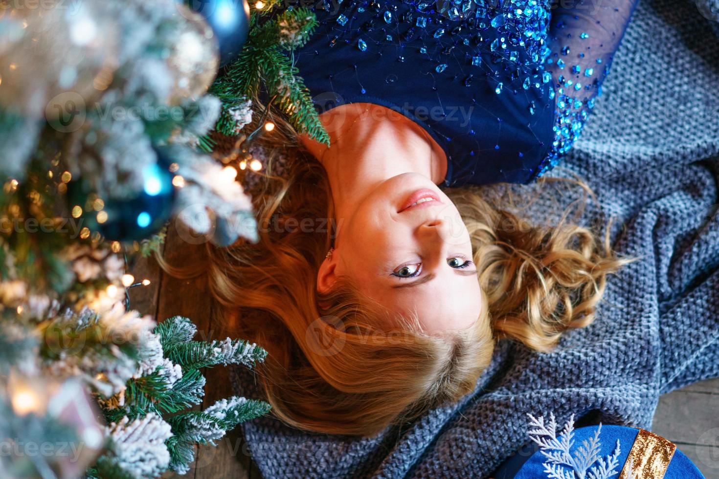 vista ad alto angolo di donna carina sdraiata sul pavimento vicino all'albero di natale con regali. foto