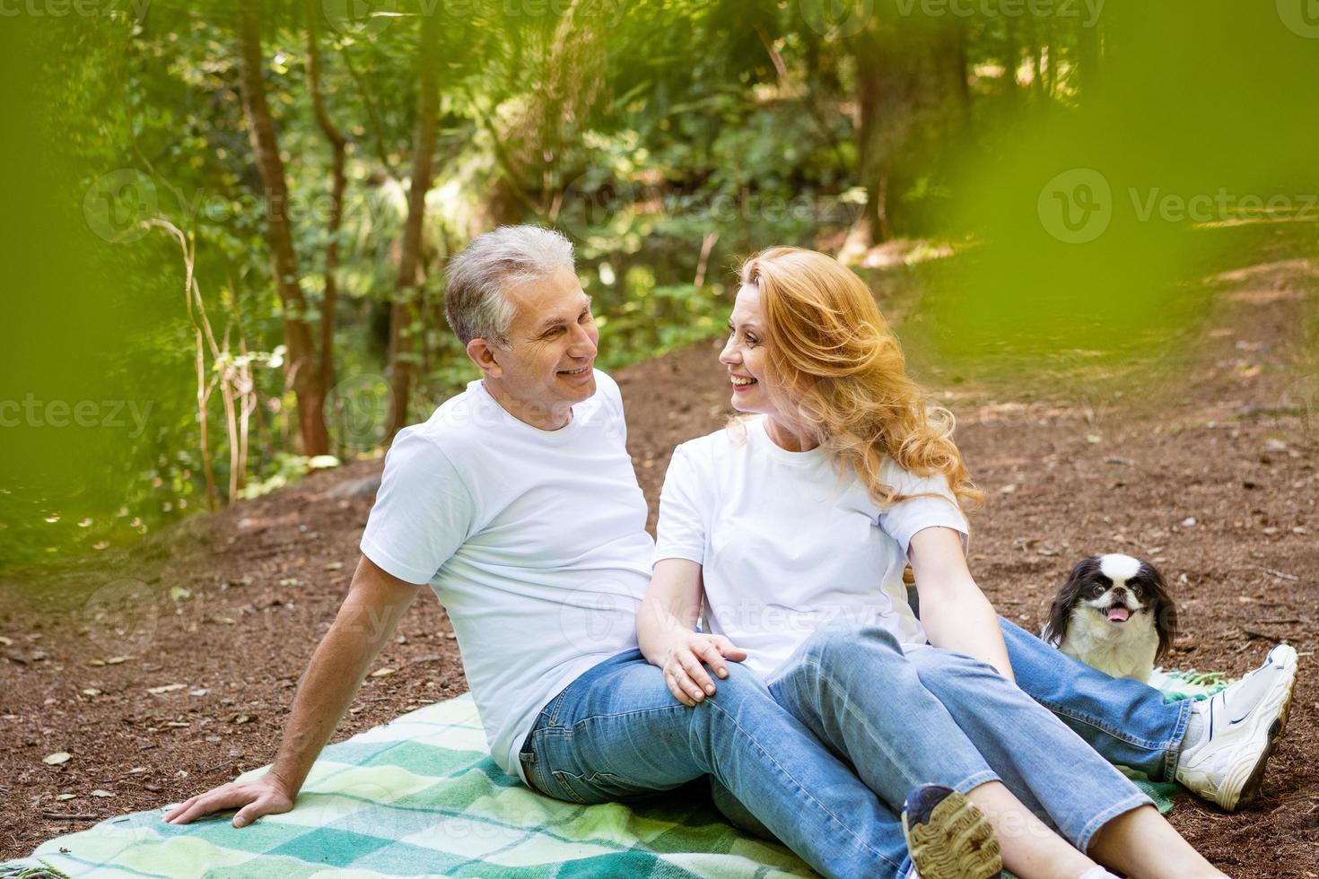 coppia matura nella foresta giacciono su una coperta con un cane foto