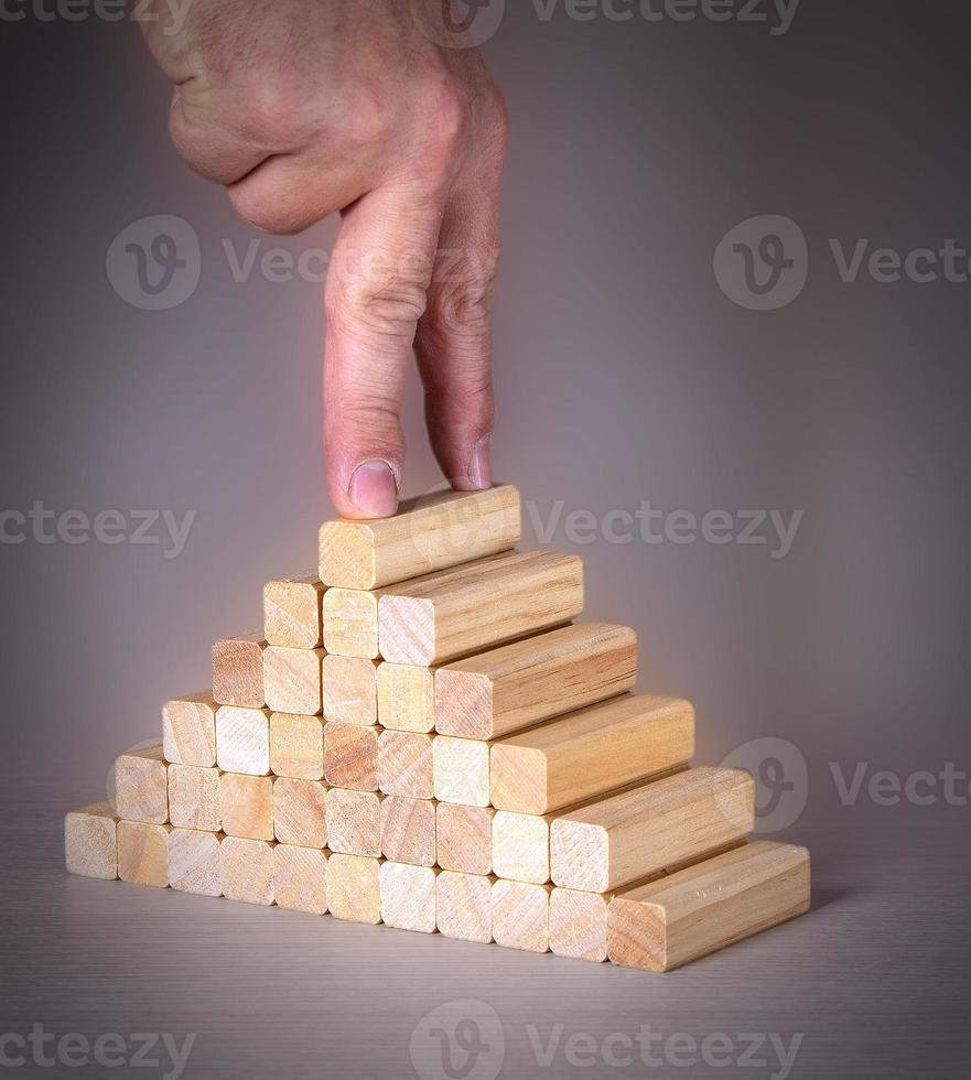 la mano maschile con due dita in cima a un piolo di legno su una scala foto