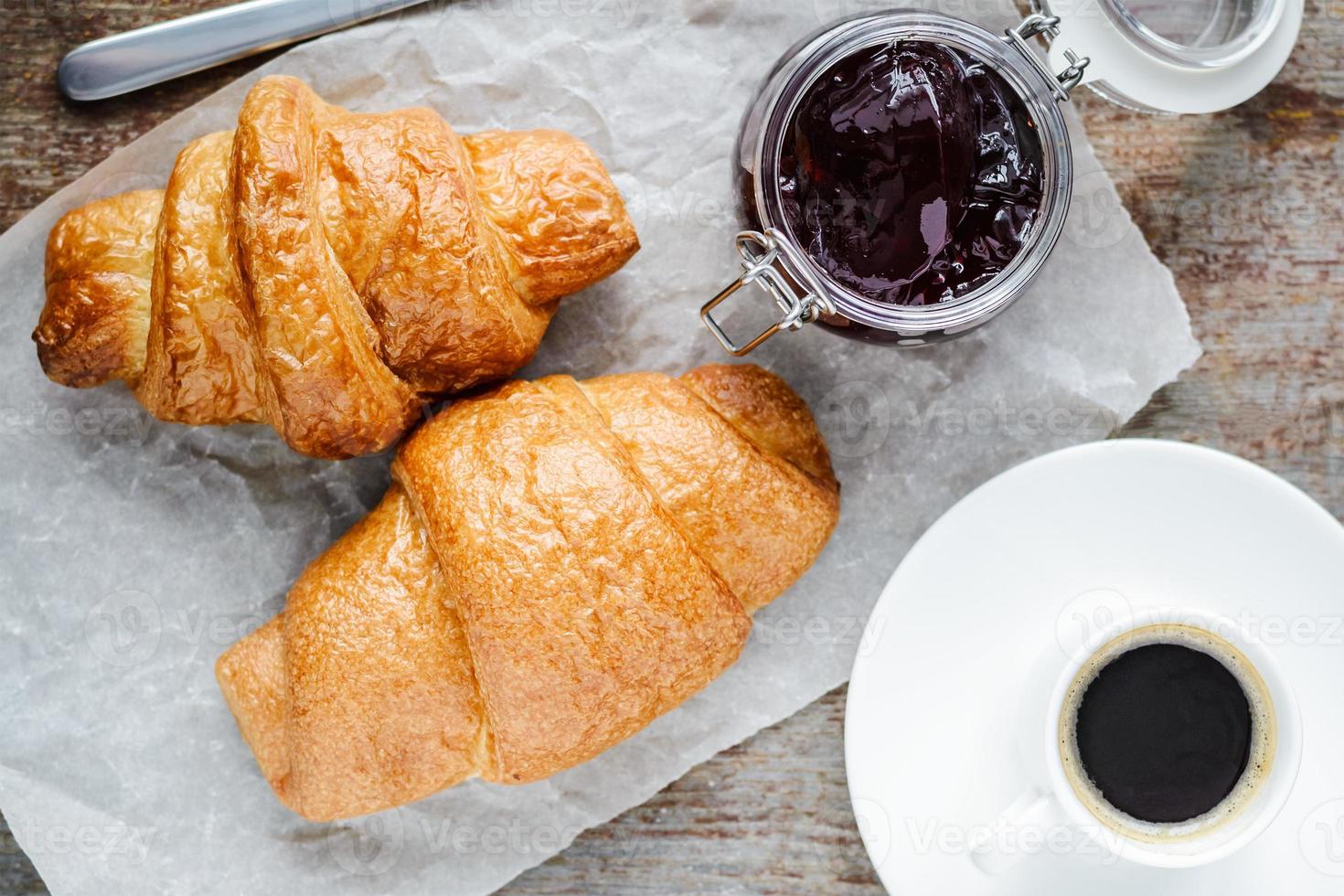 due croissant e una tazza di caffè su un tavolo di legno foto