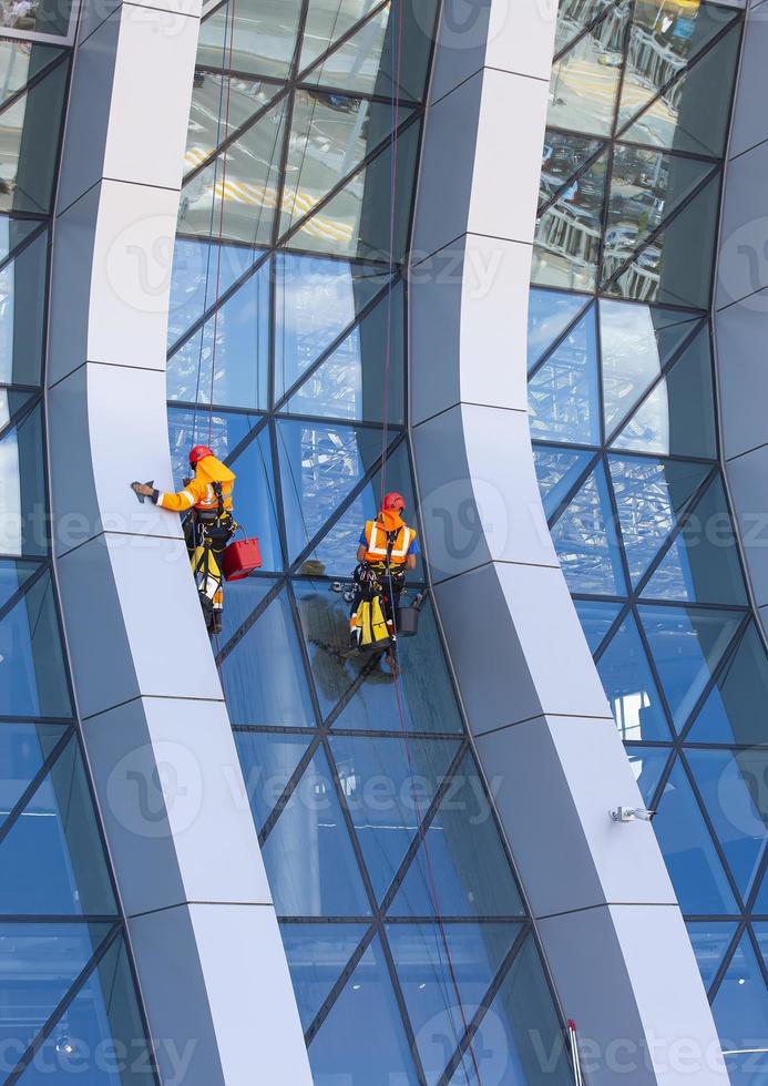 lavavetri lavorando su un moderno grattacielo di facciata in vetro foto