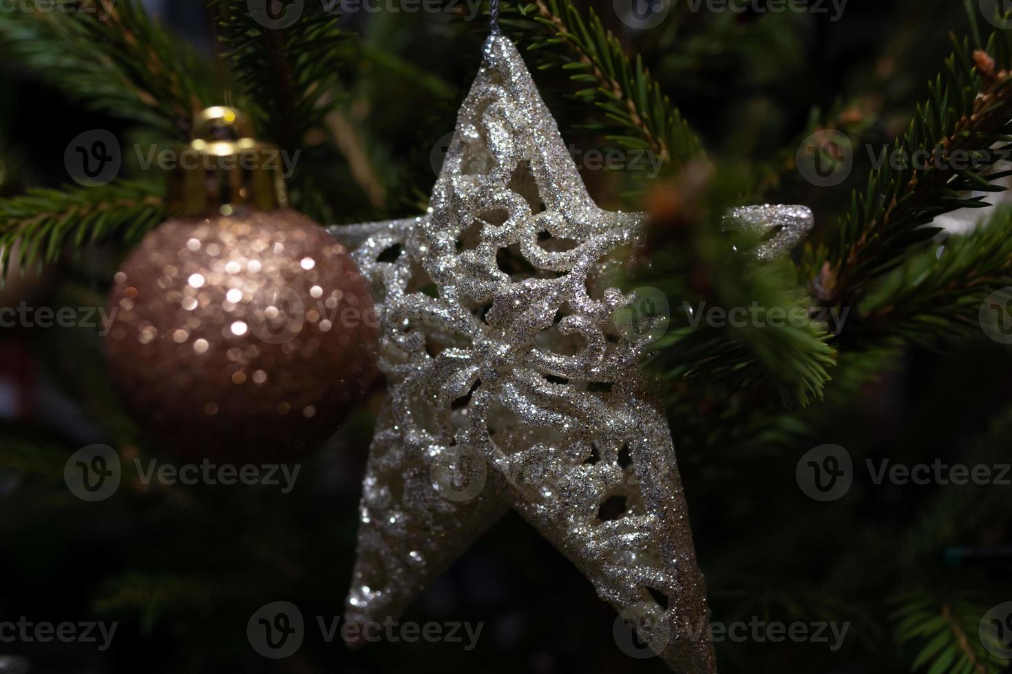 una stella d'argento lucida tra gli aghi di un albero di Natale verde con i giocattoli. sfondo festivo. foto