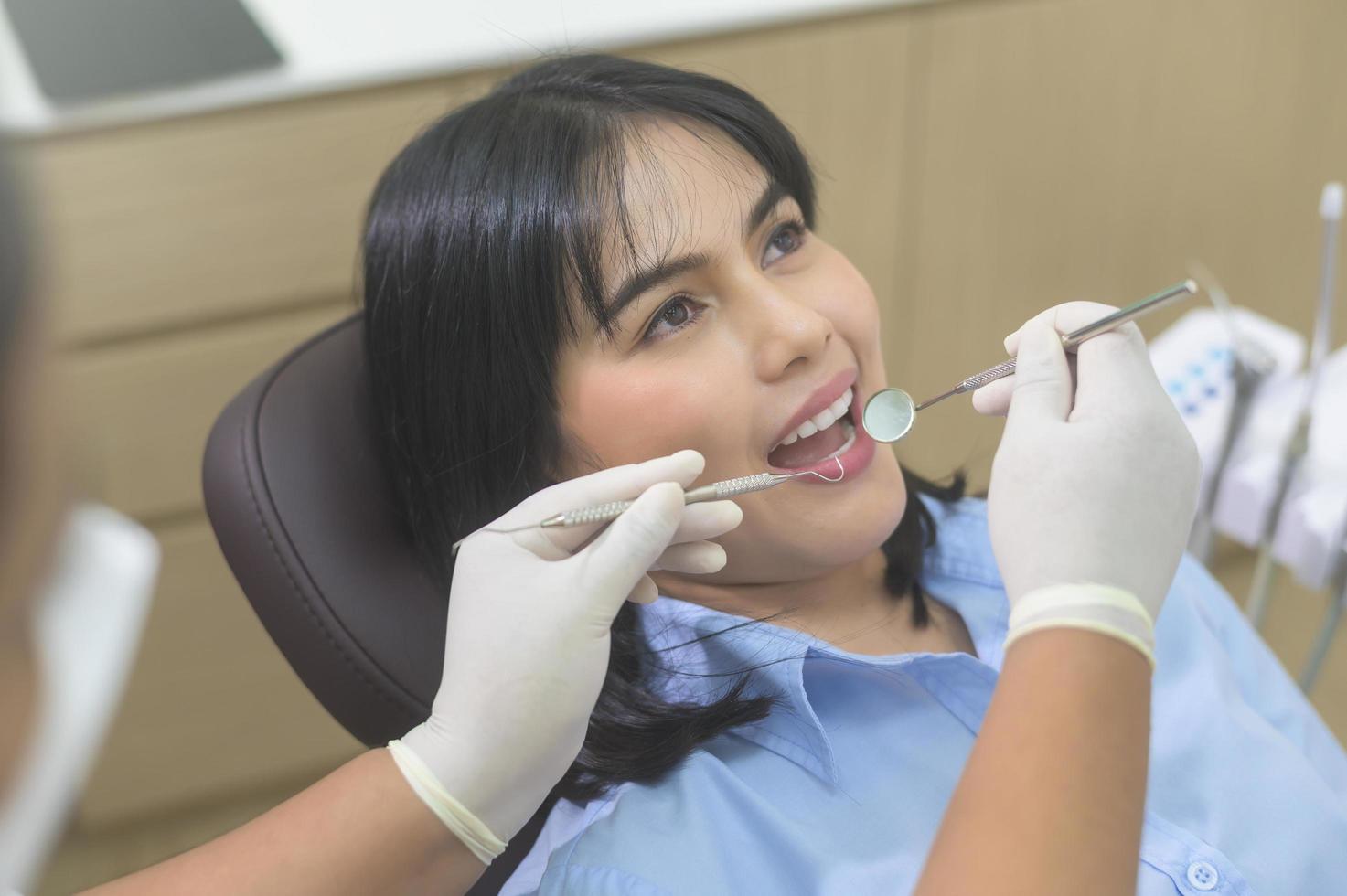giovane donna che ha i denti esaminati dal dentista in clinica odontoiatrica, controllo dei denti e concetto di denti sani foto