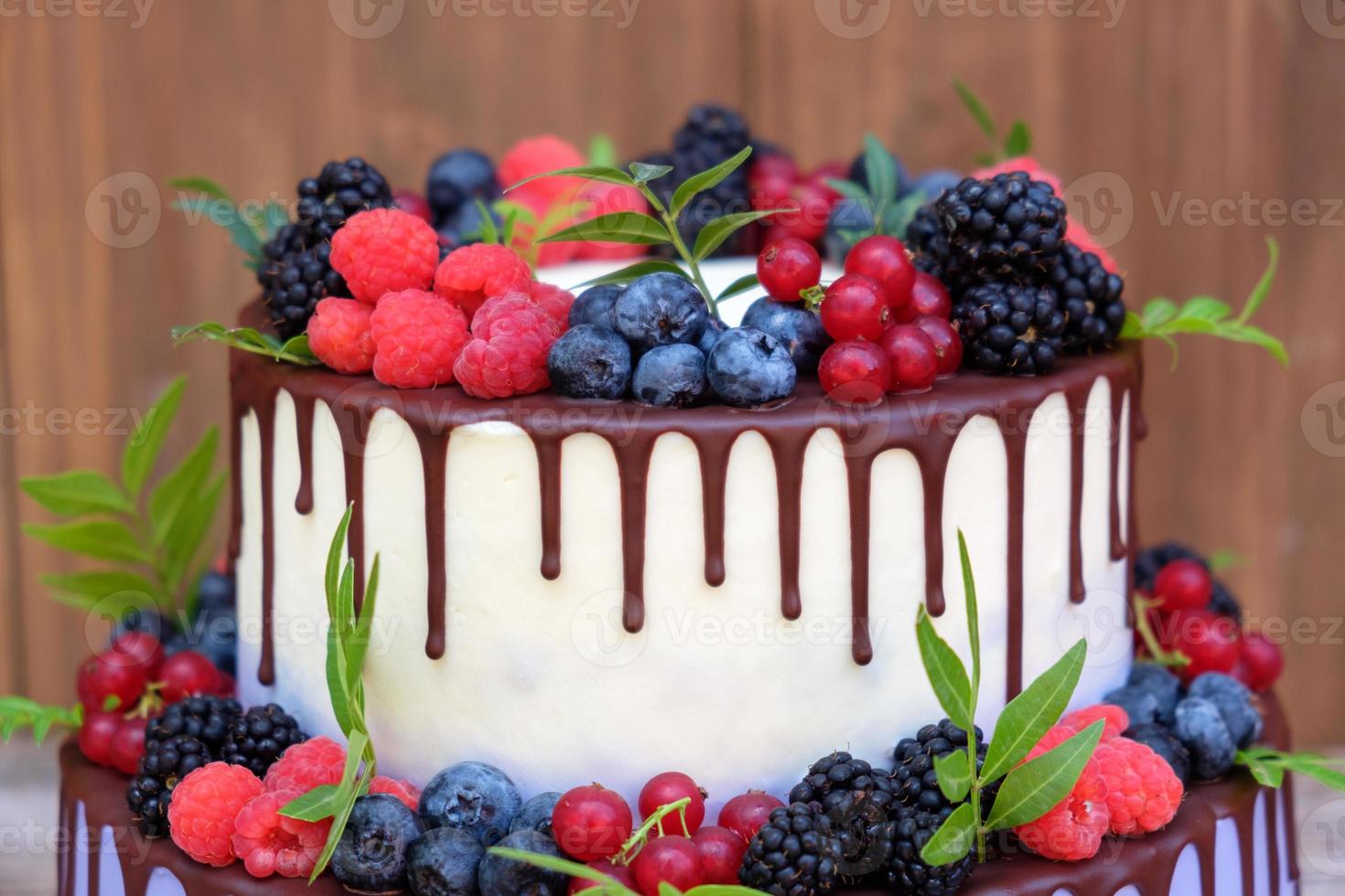 torta nuziale su due livelli con frutti di bosco freschi foto