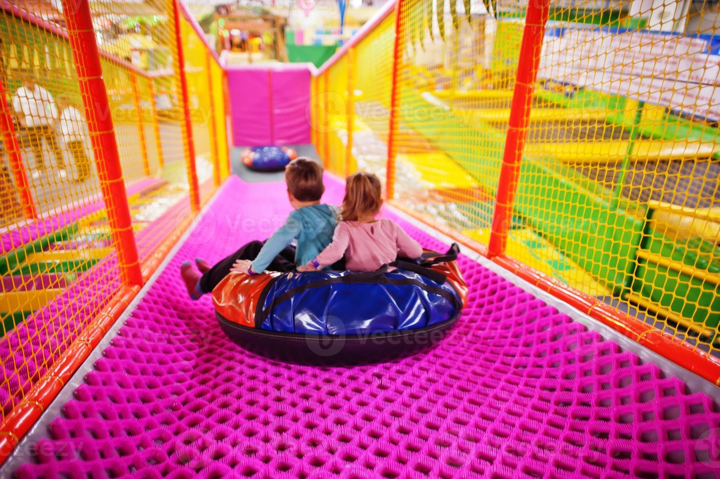 fratello con sorella seduto in ciambelle di tubi godendo di diapositive nel divertente centro per bambini. foto