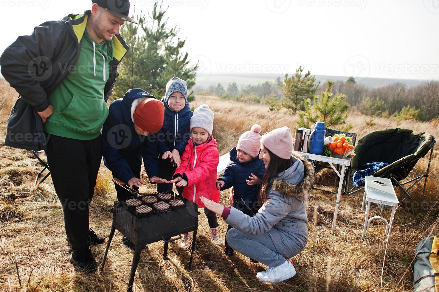 famiglia numerosa con quattro bambini al barbecue su una terrazza nella pineta. giornata barbecue con griglia. foto