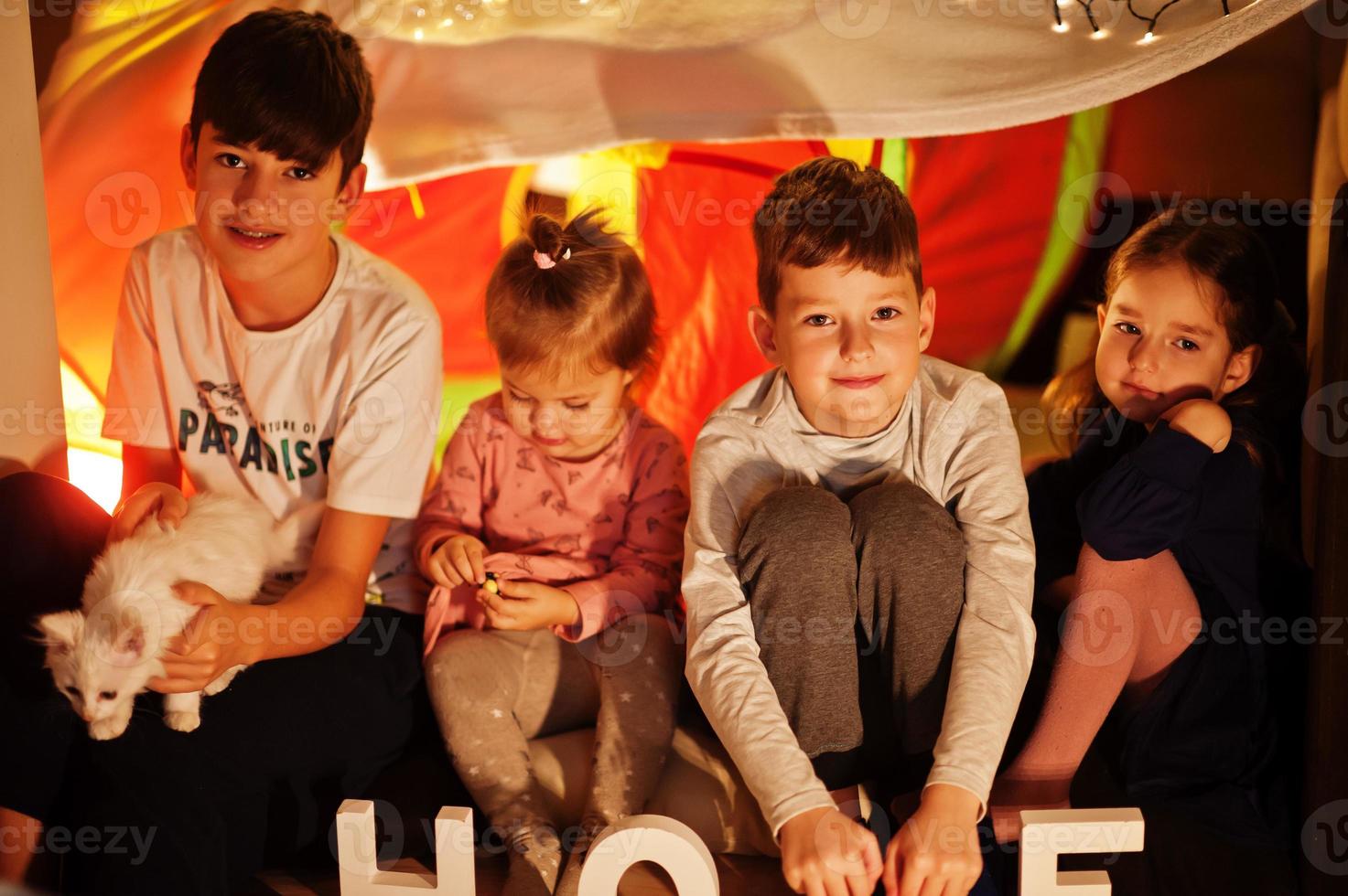 giocare ai bambini con il gattino in tenda di notte a casa. umore hygge. foto