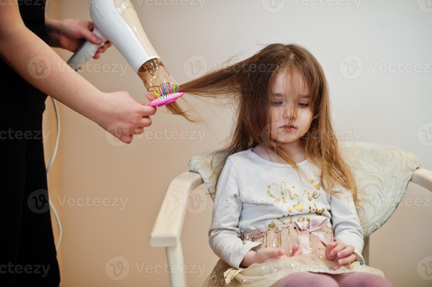 mamma e figlia fanno insieme la routine quotidiana. la madre sta spazzolando e asciugando i capelli del bambino dopo la doccia. foto