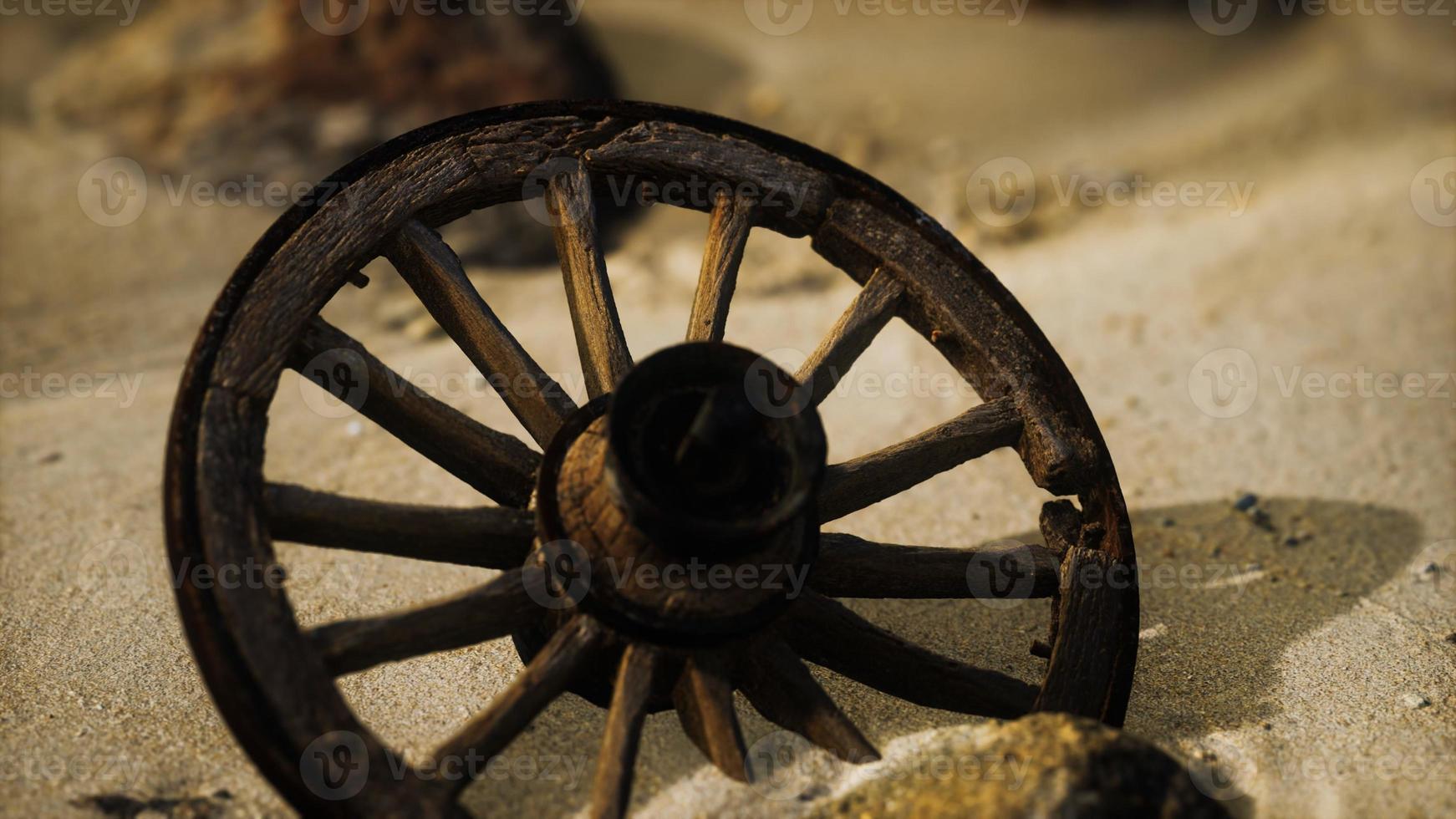 grande ruota di legno nella sabbia foto