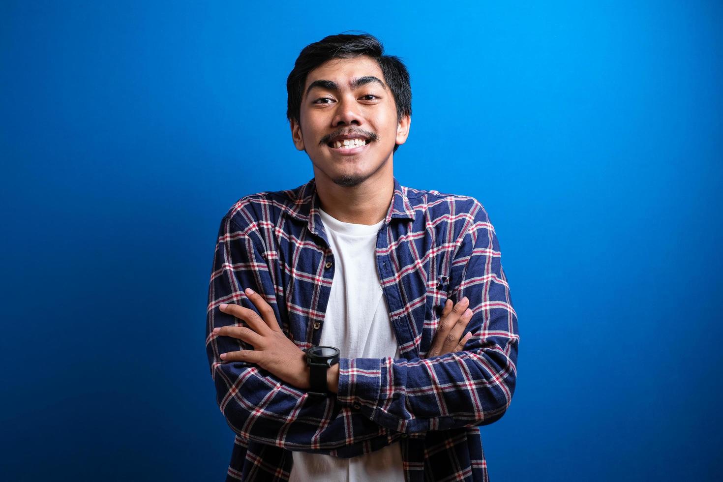 felice uomo asiatico sorride guardando la fotocamera su sfondo blu foto